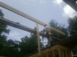 Carpenter setting a ridge beam over a new addition frame — Ice Dam Removal by Roofing Brothers in Ama