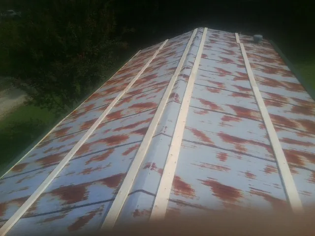 Rusted metal roof panels with new wood purlins before replacement in Ama