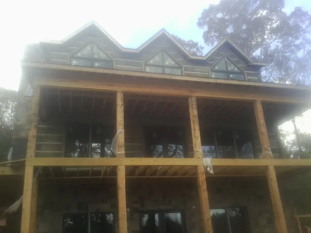 Dormers and porch framing on a large log home under construction — Roof Coating work by our crew in Ama