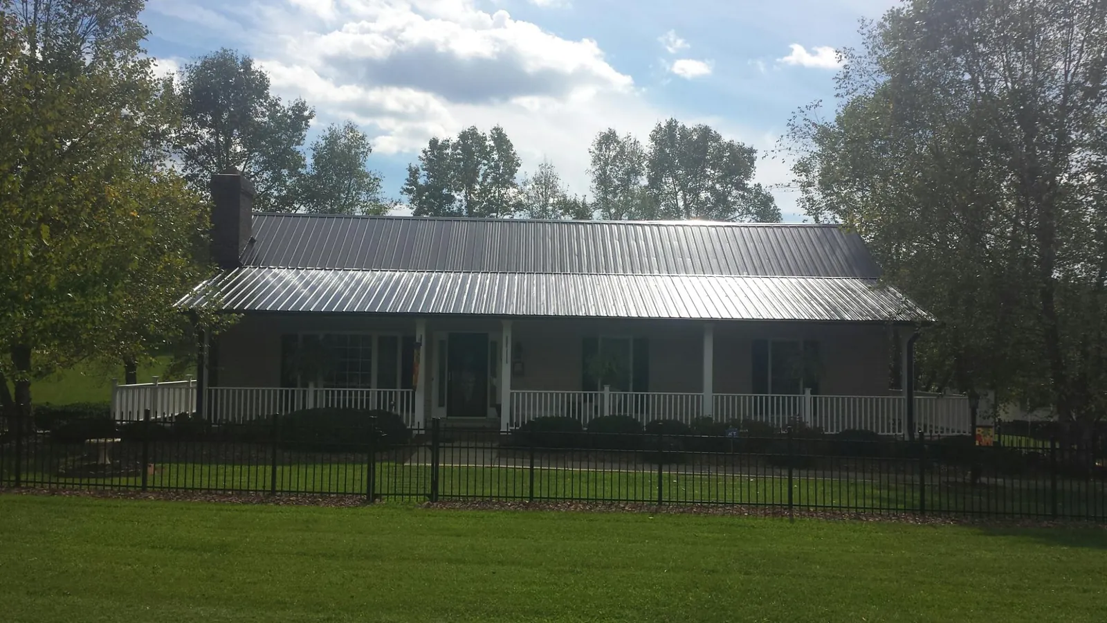 Gray metal roof on a brick ranch with a full width front porch — Gutter Guard Installation work by our crew in Ama